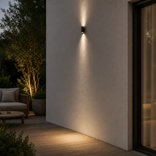 Black cylindrical outdoor wall sconce IP65 mounted on beige textured wall with dual warm light beams for patio ambiance