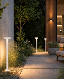 White matte outdoor ground lights with flat disc tops illuminating stone patio and gravel garden
