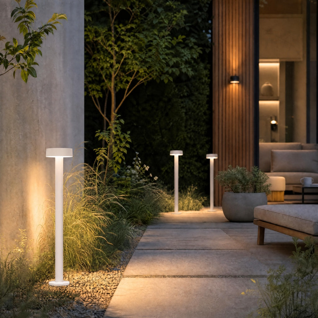 White matte outdoor ground lights with flat disc tops illuminating stone patio and gravel garden