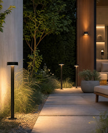 Three black outdoor lamps casting warm light on modern landscape