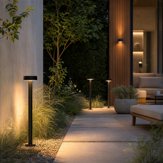 Three black outdoor lamps casting warm light on modern landscape