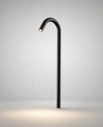 Black matte ground light with sleek cylindrical pole projecting warm LED beam