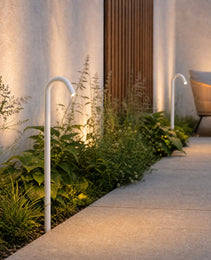 White matte outdoor path light illuminating landscaped patio and stucco wall
