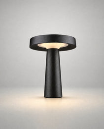 Black matte BOLLAR PRIME garden stake lamp with tapered cylindrical base and flat canopy emitting warm light