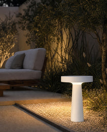 White outdoor garden stake lamp illuminating wildflowers and gravel bed in residential garden evening