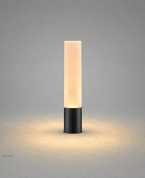 Matte black cylindrical outdoor stake light with frosted diffuser emitting warm white glow