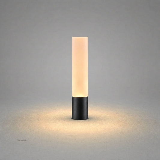Matte black cylindrical outdoor stake light with frosted diffuser emitting warm white glow