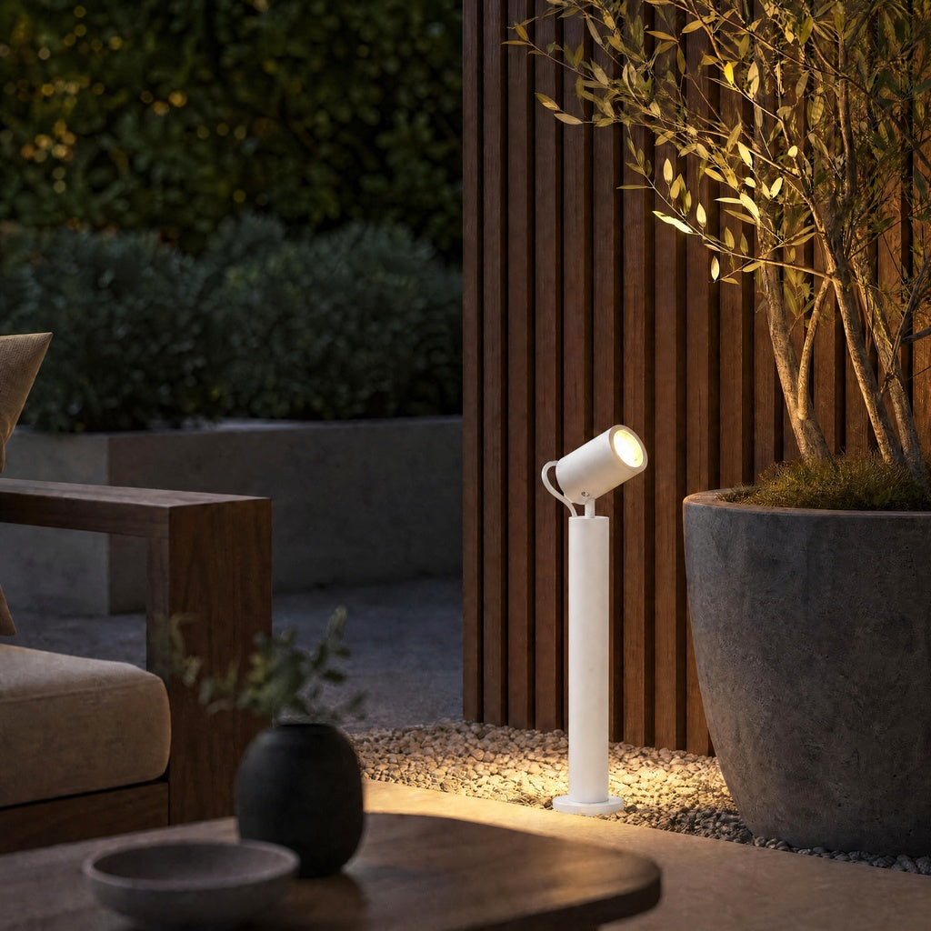 White outdoor bollard light with adjustable spot head on gravel patio
