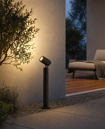 matte black outdoor bollard light with adjustable spot head installed on gravel patio