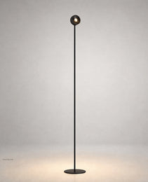 Black matte floor lamp with spherical LED head and warm glow on gray studio background
