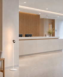 White floor lamp in modern hotel lobby beside wooden armchair casting ambient light