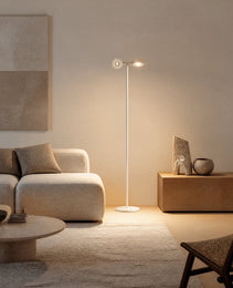 White matte mobile projection floor lamp with dual adjustable heads emitting warm ambient light in minimalist interior