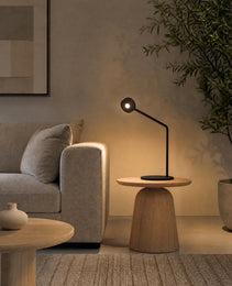 Black matte desk lamp with circular head on wooden side table in living room