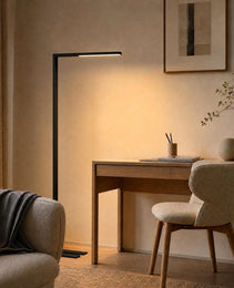 Black matte C-shaped floor lamp with horizontal LED bar illuminating home office desk workspace