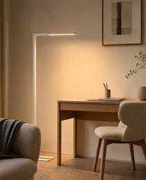White matte minimalist floor lamp providing warm task lighting over wooden study desk