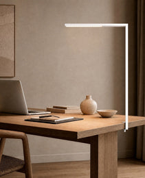 White matte L-shaped floor lamp clipped to oak desk in uncluttered study setting