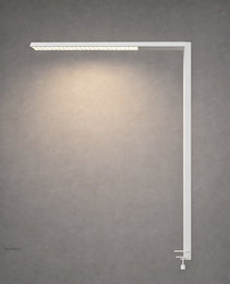 White matte L-shaped desk lamp with adjustable clamp on gray concrete wall