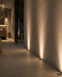 Black GU10 MR16 recessed floor lights creating vertical warm pools on concrete pathway
