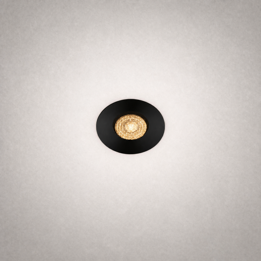 Black GU10 MR16 recessed ceiling light with matte trim and gold reflector casting warm glow