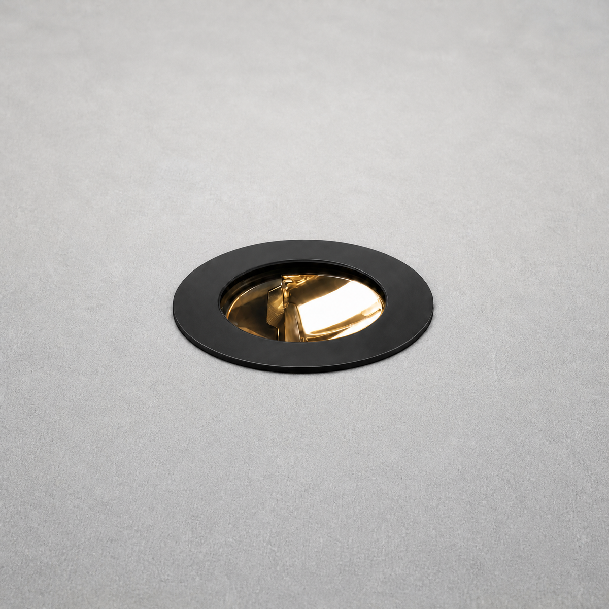 Black matte trim recessed floor light with gold reflector flush mounted in concrete