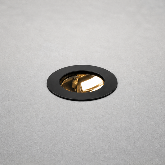 Black matte trim recessed floor light with gold reflector flush mounted in concrete