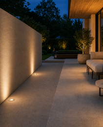 DECK PRIME 1711 recessed floor light casting warm glow on beige stone patio at night