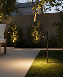 Black outdoor LED garden spike casting warm glow on lawn and shrubs