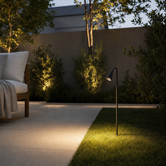Black outdoor LED garden spike casting warm glow on lawn and shrubs