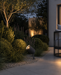 Black matte exterior spike lamp casting warm glow on purple flowering plants