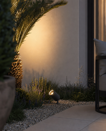Dark grey textured garden spike light casting warm glow on wall