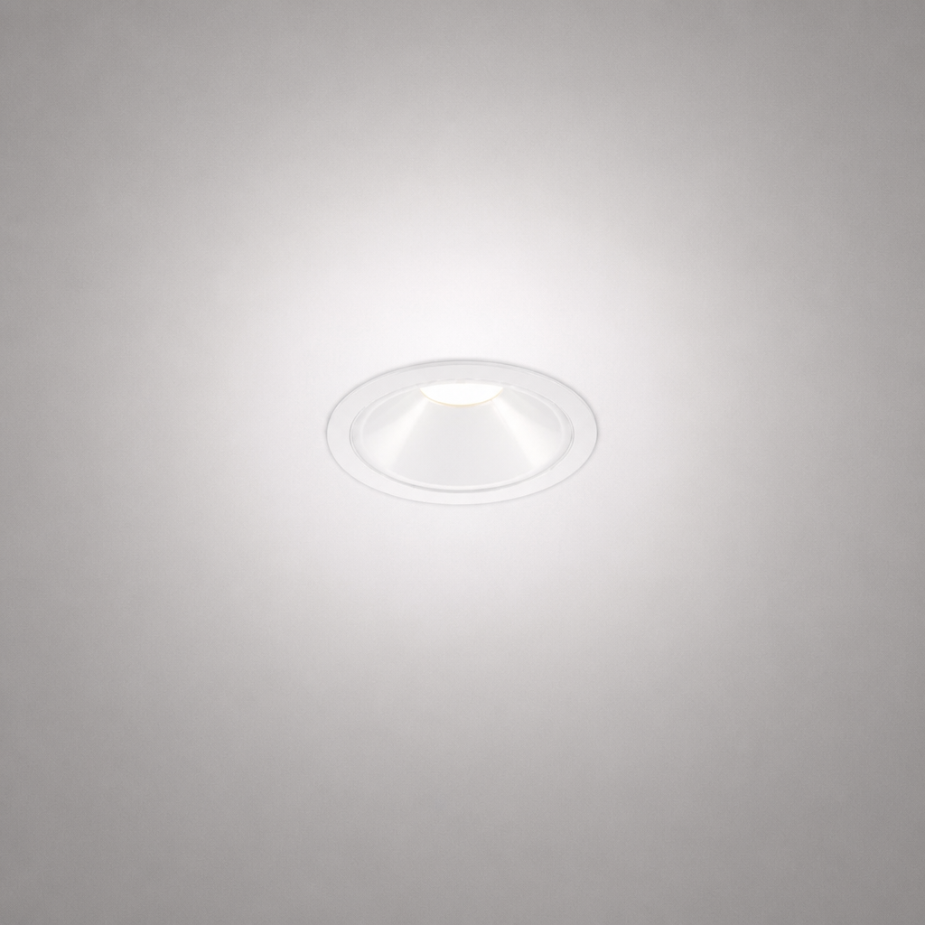 White matte trim recessed spotlight emitting warm white glow on textured gray ceiling