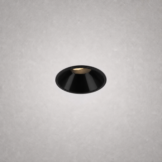Close-up black matte finish recessed ceiling light against gray textured ceiling