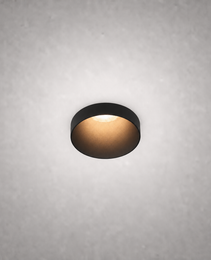 Matte black semi-recessed ceiling spotlight with warm glow on textured gray ceiling