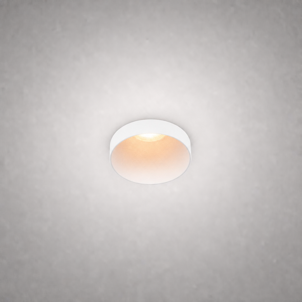Matte white semi-recessed ceiling spotlight with soft golden light on light gray ceiling