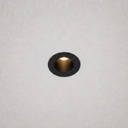 close-up black trim ring DOT PRIME 1839 recessed light with gold reflector on textured ceiling