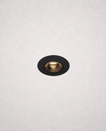 Close-up black trimless recessed LED fixture with warm gold reflector in white ceiling