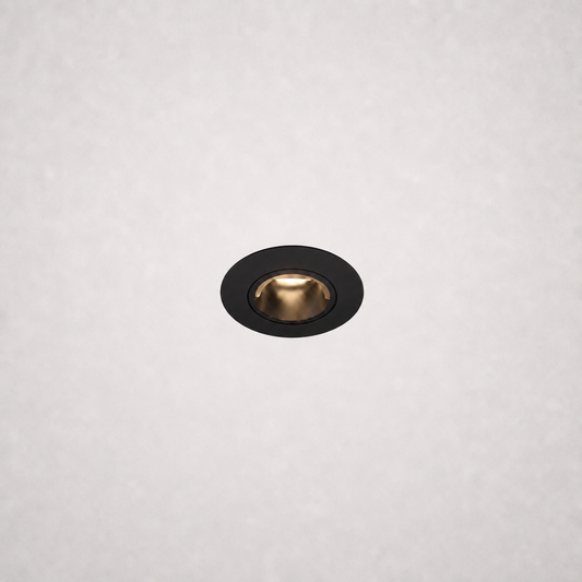 Close-up black trimless recessed LED fixture with warm gold reflector in white ceiling