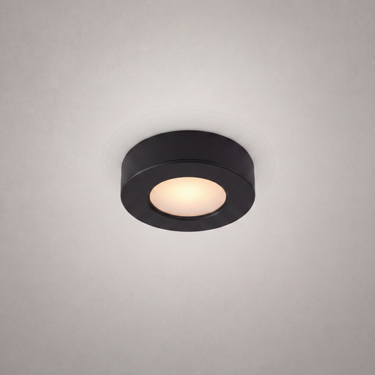 close-up matte black ultra-thin circular surface-mount recessed luminaire with diffused warm white glow