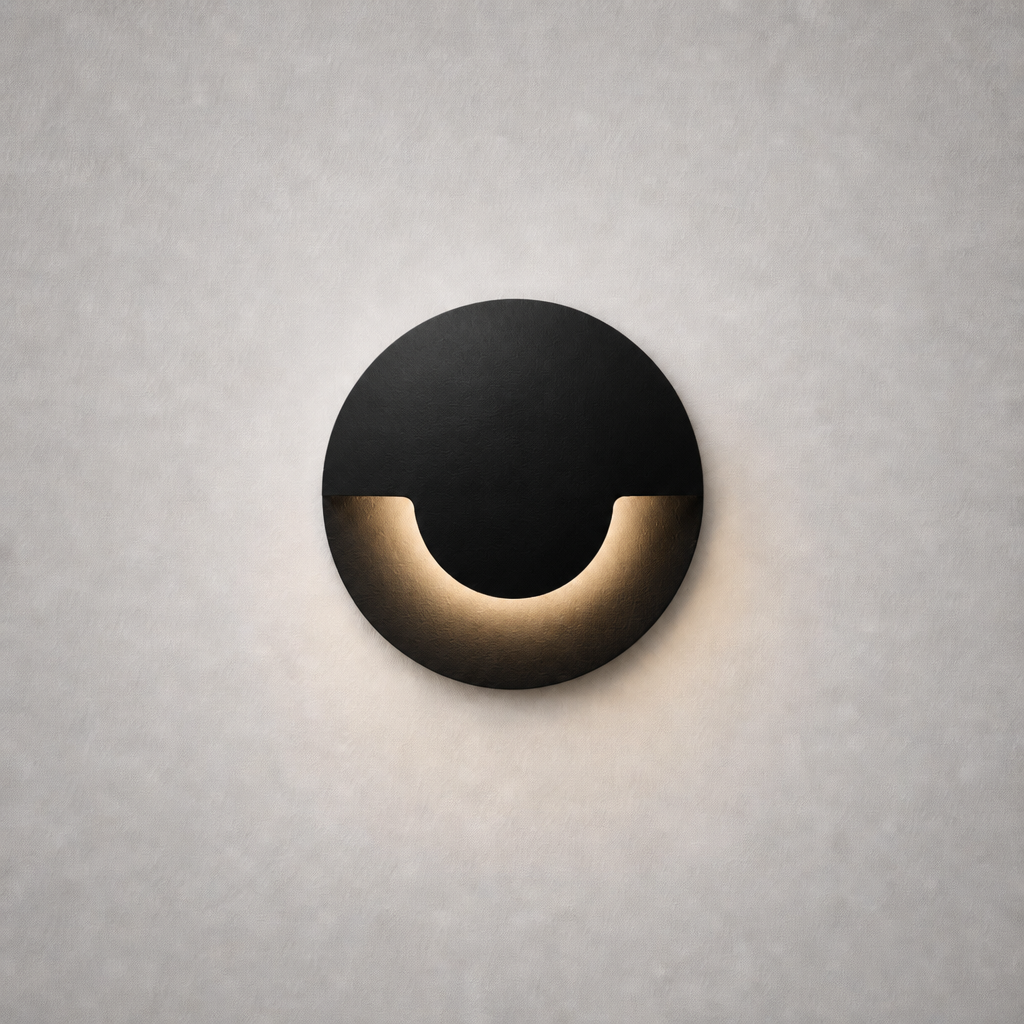 matte black circular recessed wall sconce with warm golden glow and geometric silhouette
