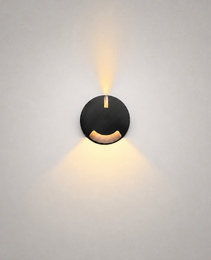 Close-up black architectural step light showing vertical slot and curved cutout for dual-directional warm lighting