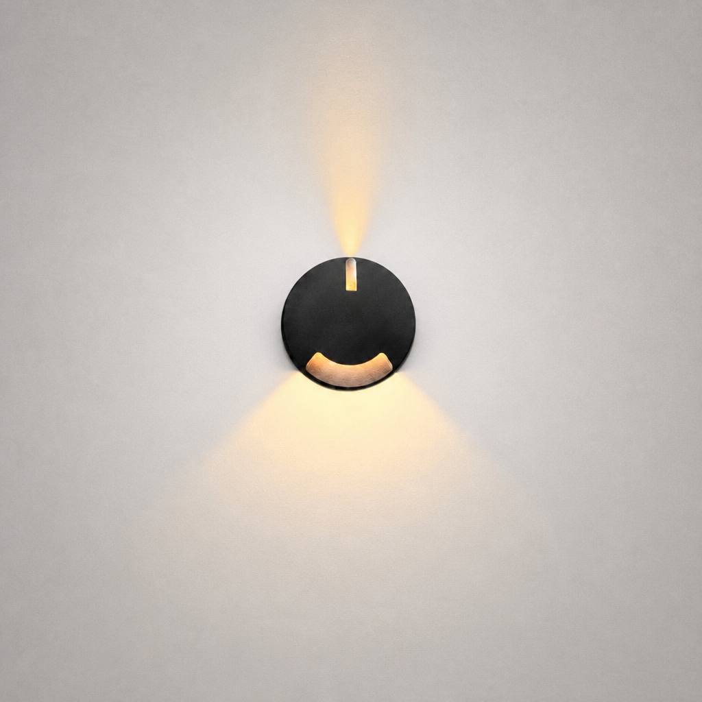 Close-up black architectural step light showing vertical slot and curved cutout for dual-directional warm lighting
