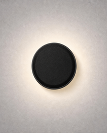 Matte black circular low voltage step light with woven texture emitting warm white glow