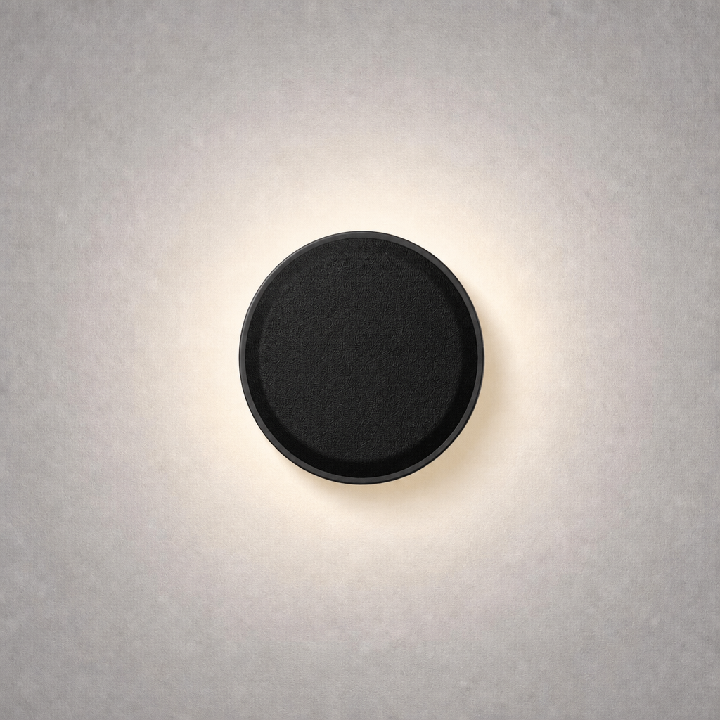 Matte black circular low voltage step light with woven texture emitting warm white glow