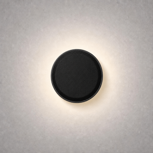 Matte black circular low voltage step light with woven texture emitting warm white glow