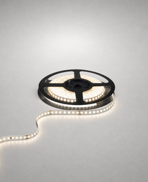 Coiled warm white 14.4W IP20 LED strip light on black spool with visible SMD LEDs and copper pads