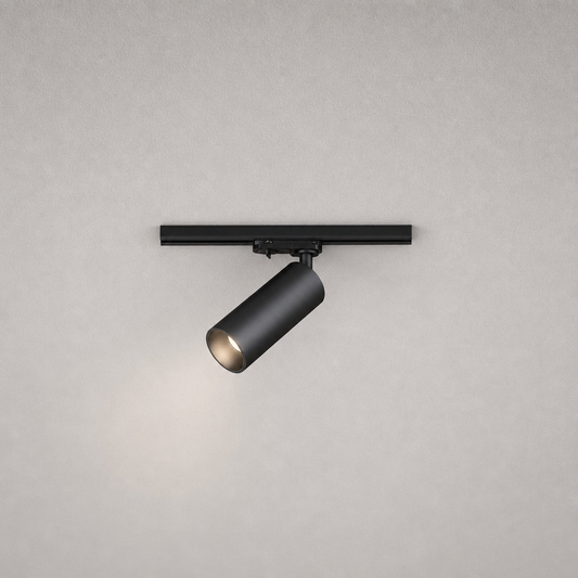 Close-up black matte cylindrical track spotlight showing mounting hardware and warm light