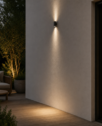 Black cylindrical outdoor wall sconce IP65 mounted on beige textured wall with dual warm light beams for patio ambiance