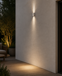 White cylindrical outdoor wall sconce IP65 installed on off-white stucco wall casting soft vertical glow for residential patio