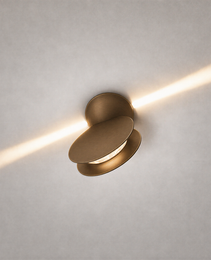 Matte brass oval ceiling light fixture casting diagonal warm beam on textured ceiling