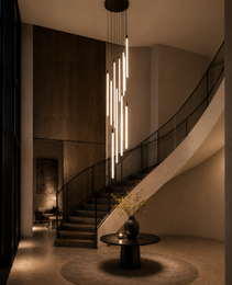Black metal linear LED chandelier with cascading tubes over curved staircase, warm white light for modern lobby verticality